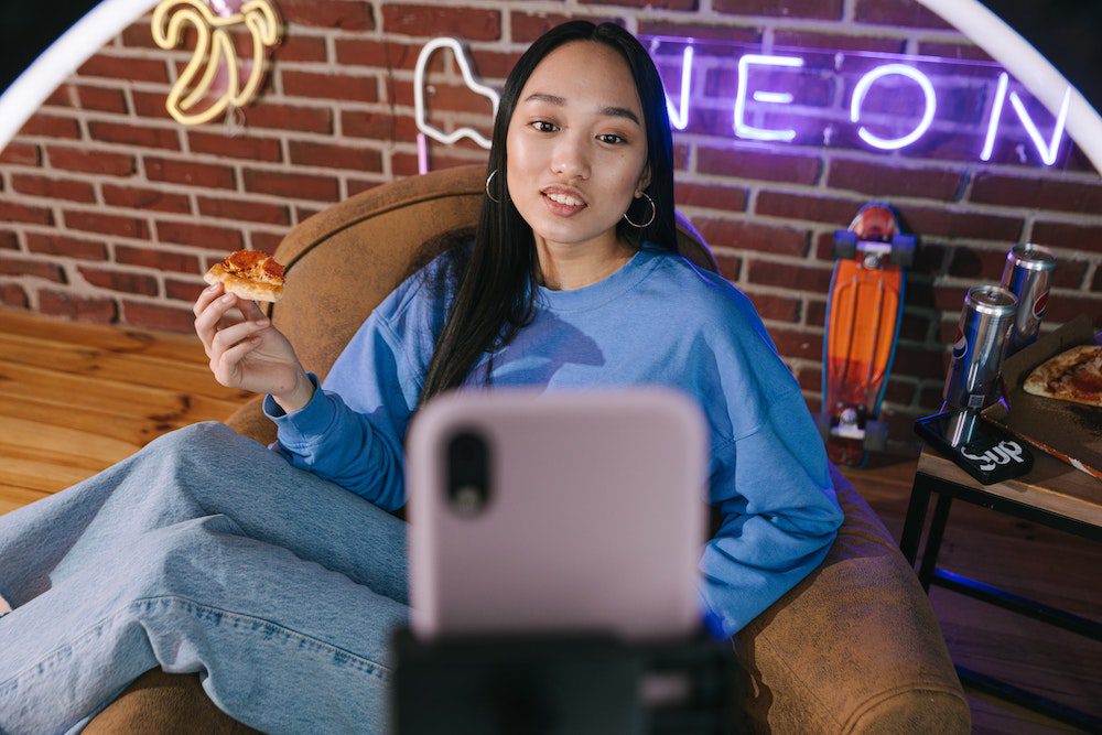 Brand ambassador in front of her iphone creating user-generated content about a pizza