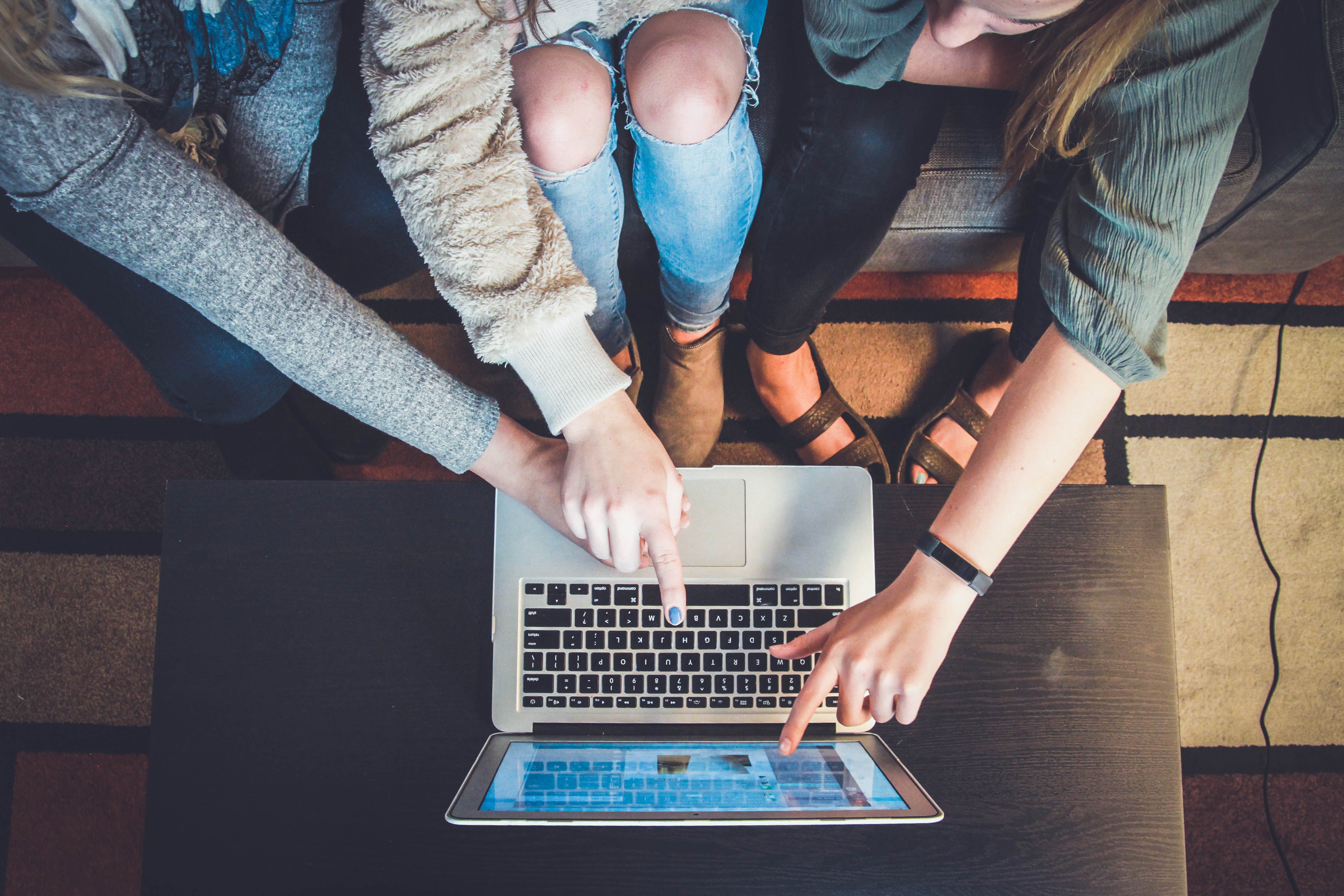 Three women pointing at a laptop and looking at a brand's website